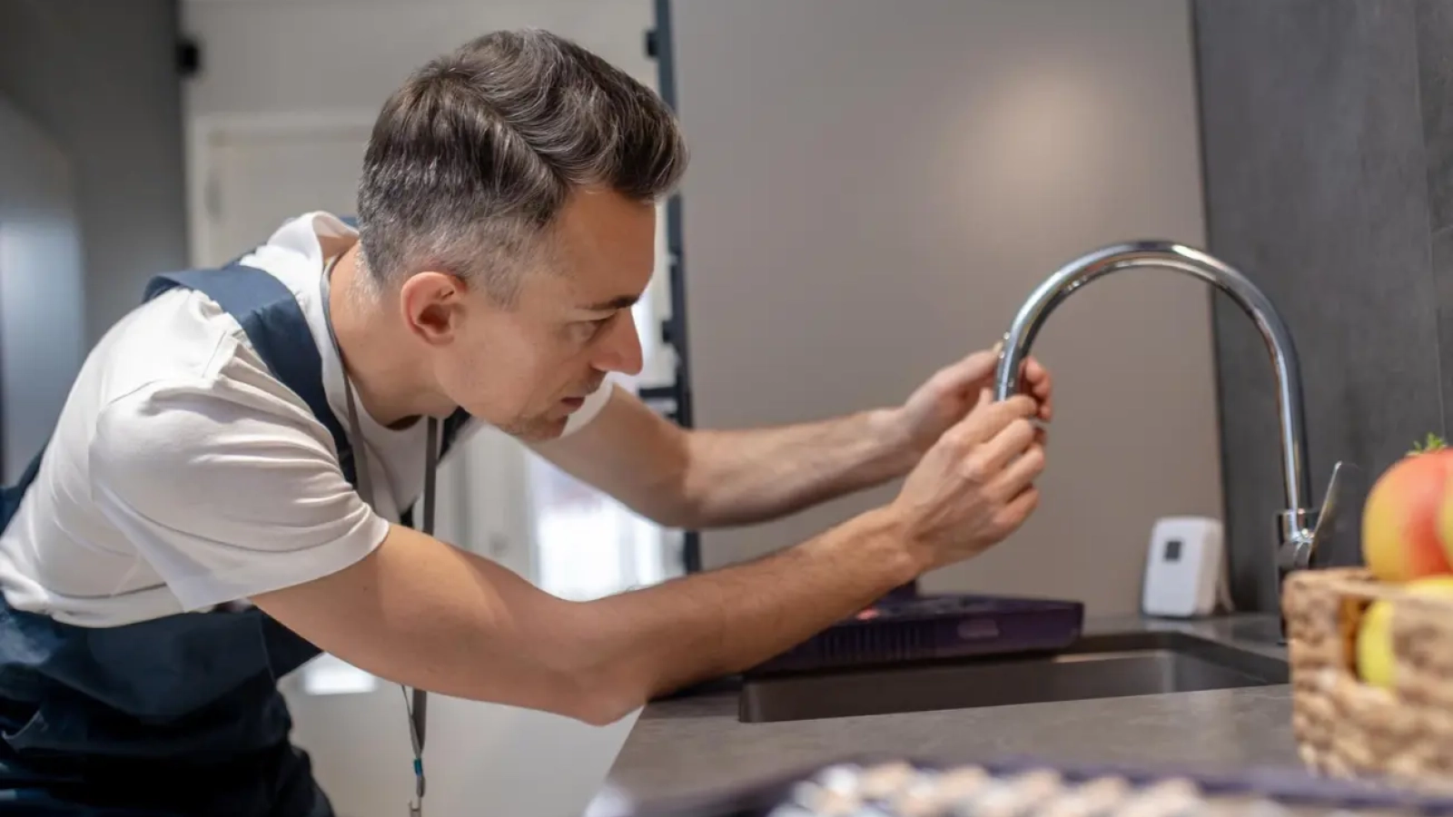 A plumber repairing a dripping tap of kitchen at home in Dubai
