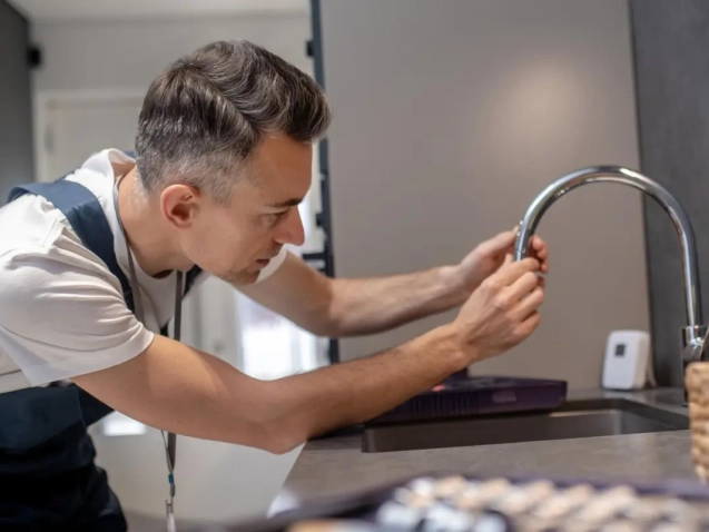 A plumber repairing a dripping tap of kitchen at home in Dubai